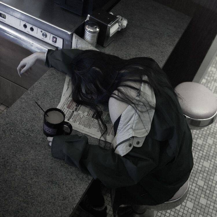 Foto de perfil triste de mujer con la cabeza gacha en un café