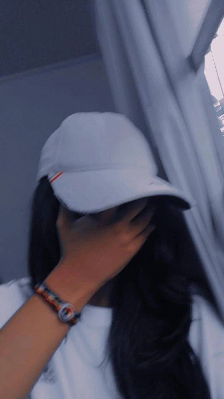 Foto de Perfil Feminino com Boné e Mão no Rosto