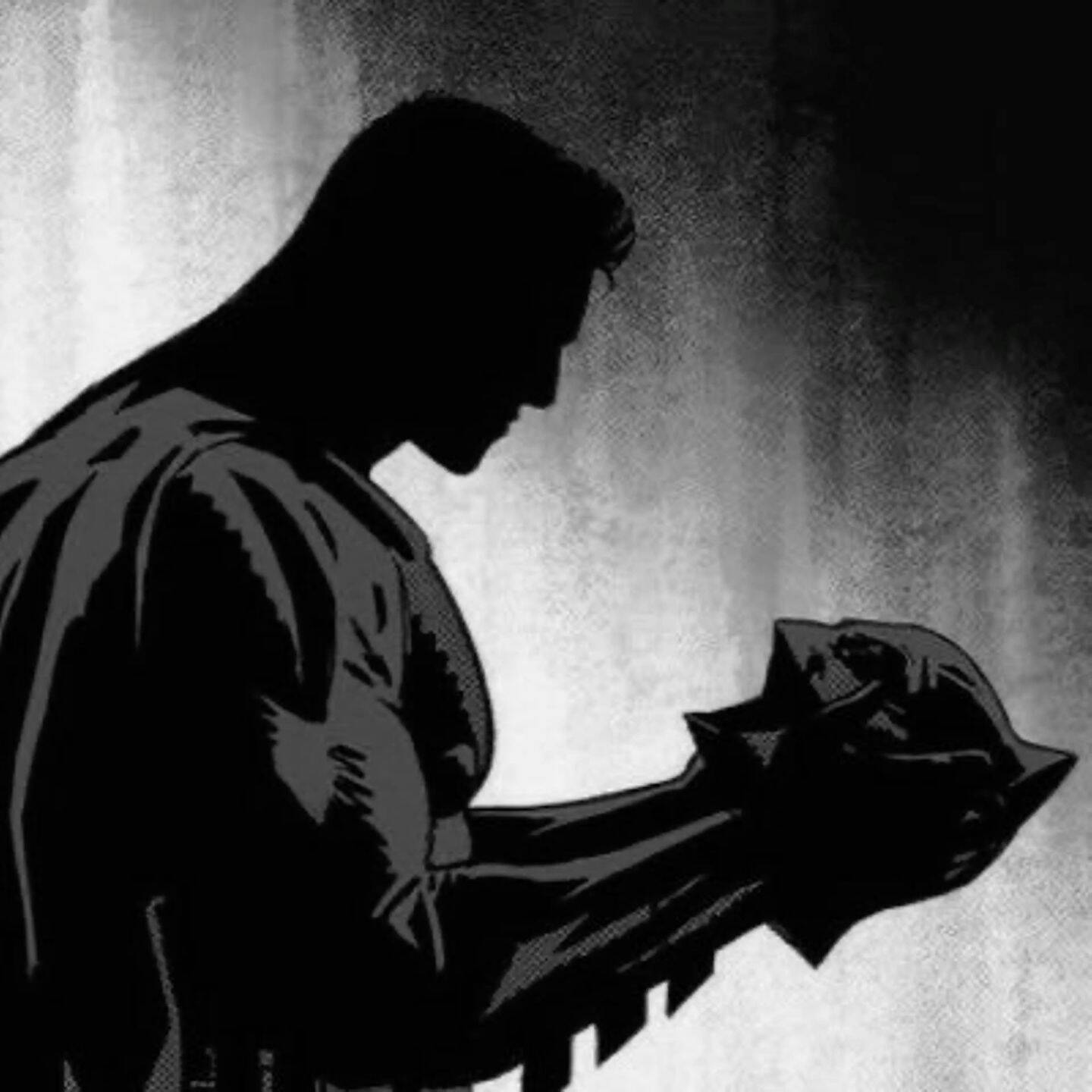 Foto de perfil de Batman sosteniendo la máscara
