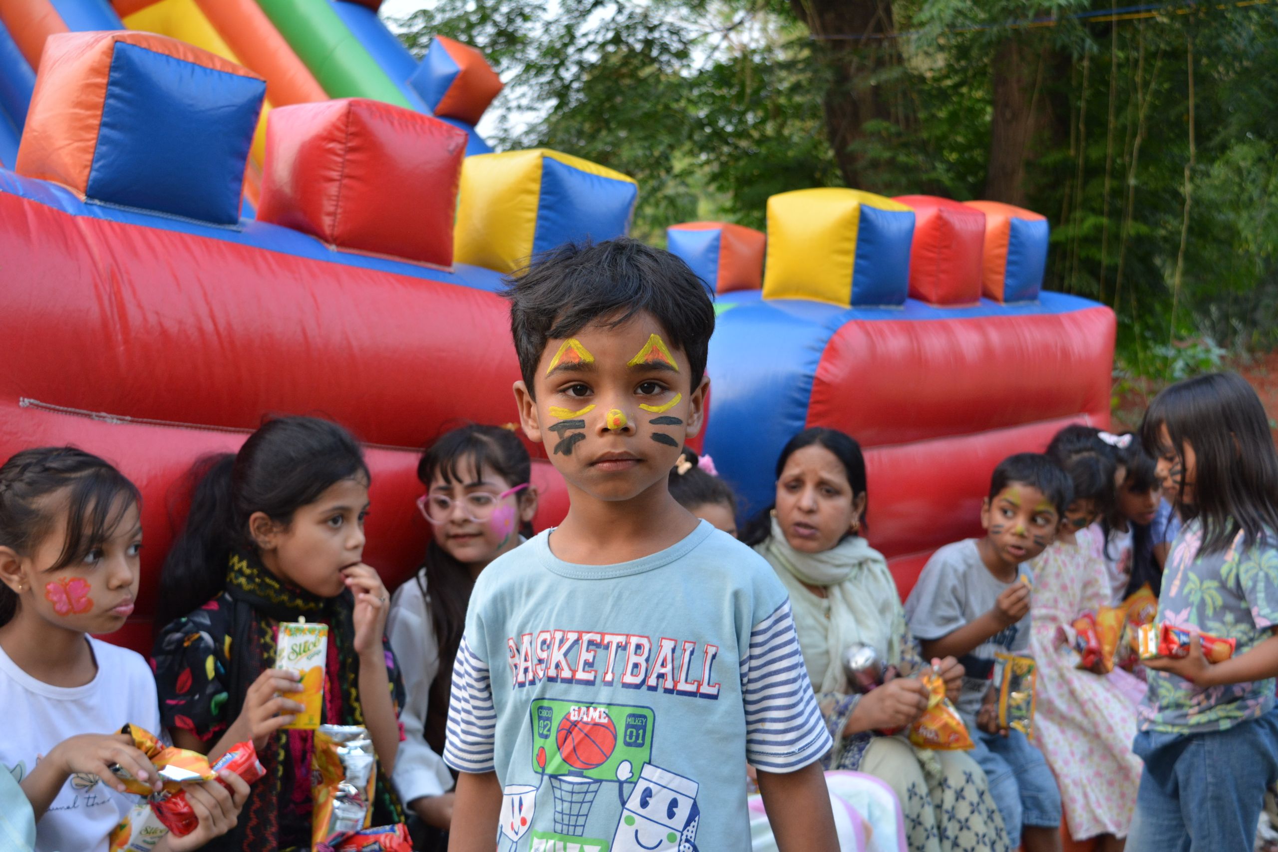 I bambini si divertono con una vivace festa di compleanno all'aperto con truccabimbi e scivolo gonfiabile.