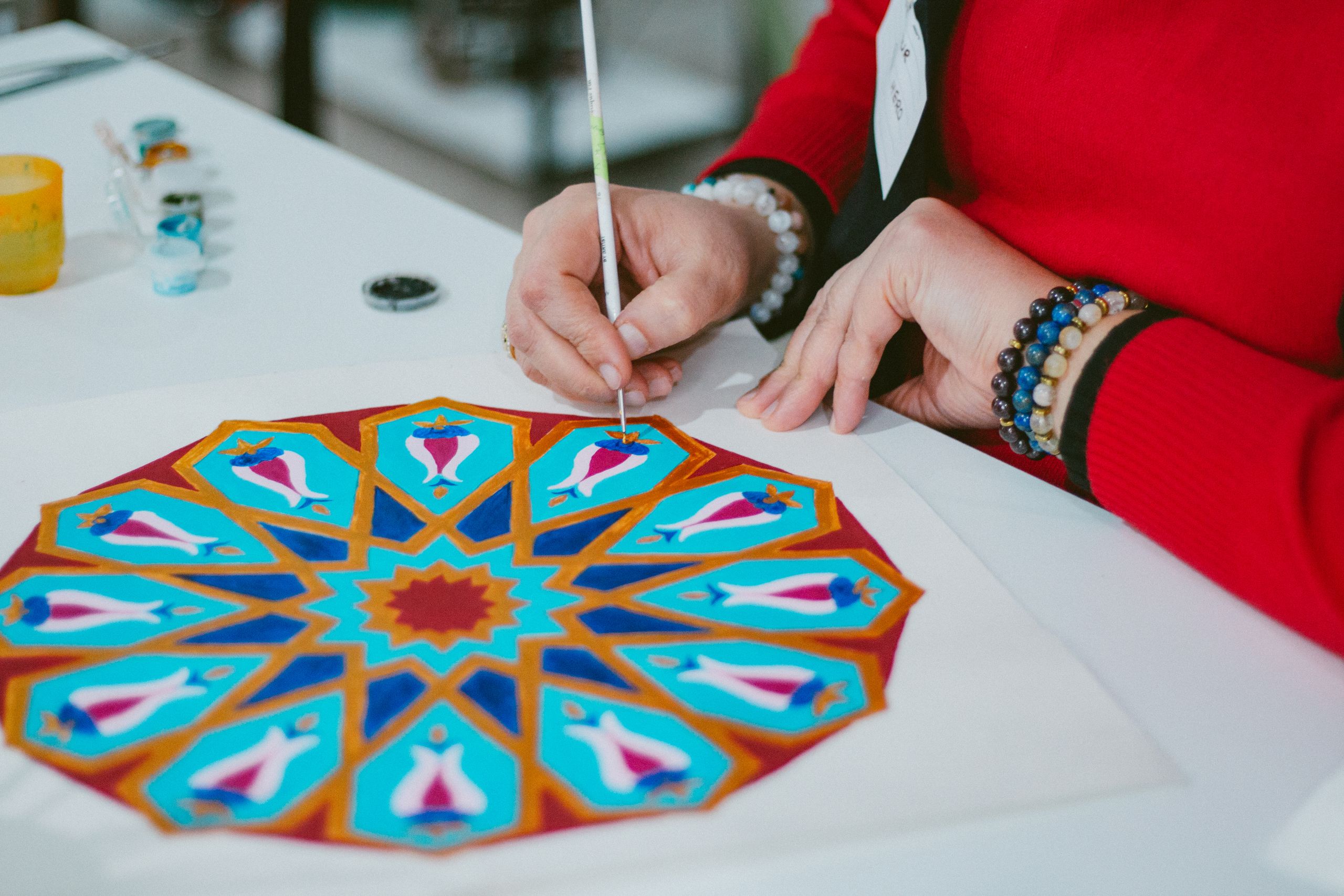 Manos pintando un colorido diseño de mandala con precisión y habilidad.