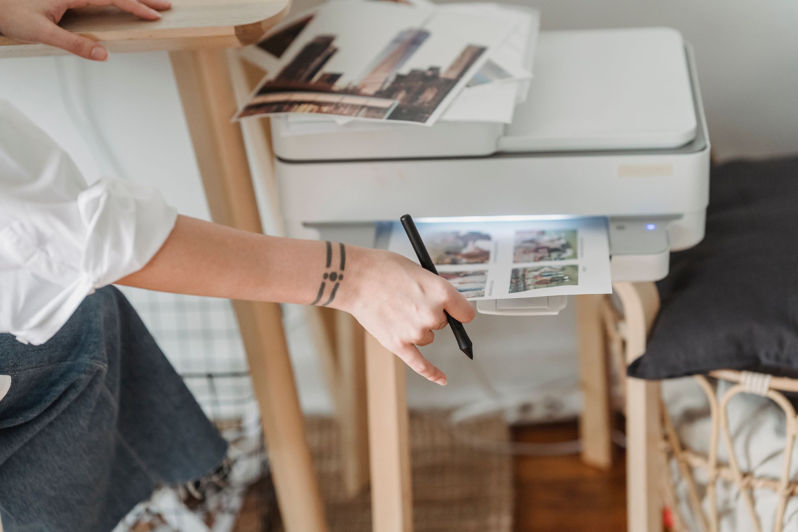 Anonyme Fotografin aus einem hohen Winkel des Ausschnitts, die einen Drucker zum Erstellen von Bildern verwendet, während sie in einer Wohnung arbeitet